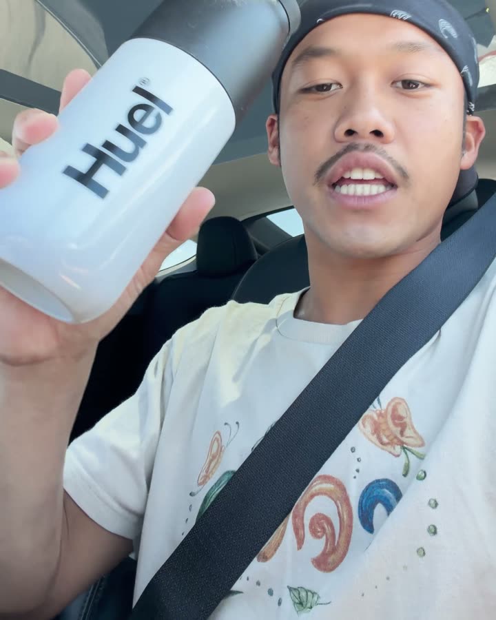 Oak holding a Huel bottle in the car